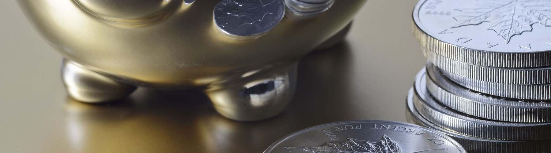 A chrome piggy bank and silver bullion coins