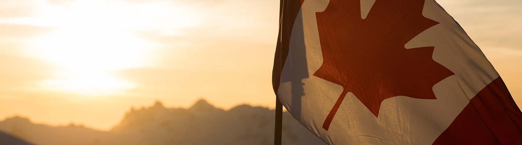 Canadian flag in the mountains at sunset