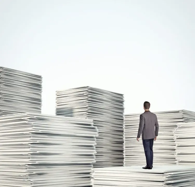 Fotolia_65657824_businessman-standing-on-a-pile-of-documents_M-e1464360639947