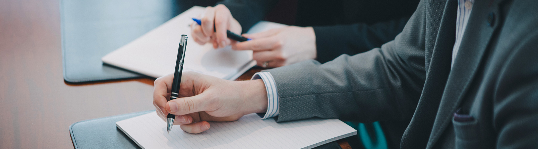 A business person writing on a pad of paper